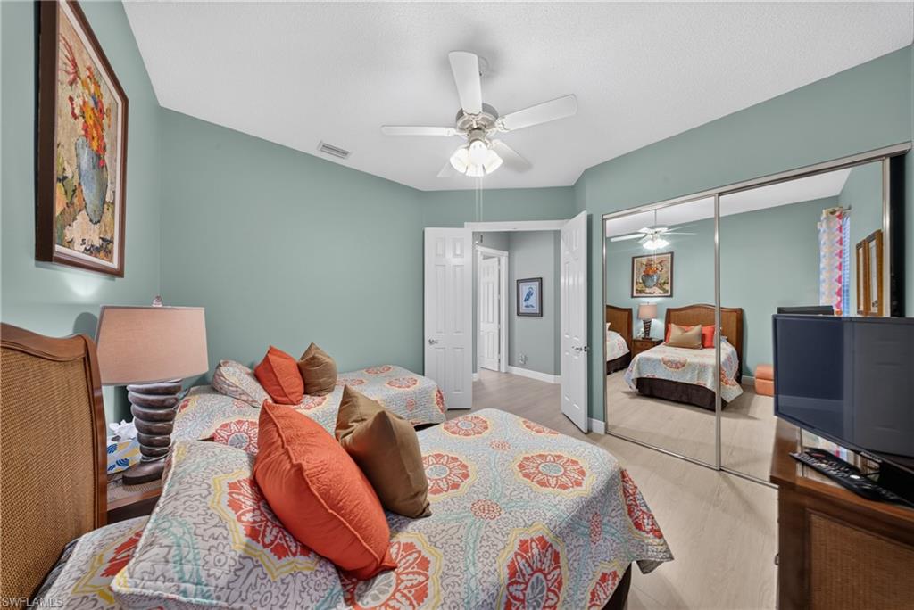 Bedroom featuring vaulted ceilings, wood-finish flooring, a ceiling fan, and sliding mirrored closet doors