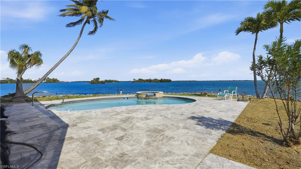 View of swimming pool with a pool with connected hot tub, a patio area, and a water view - Virtually Edited Image