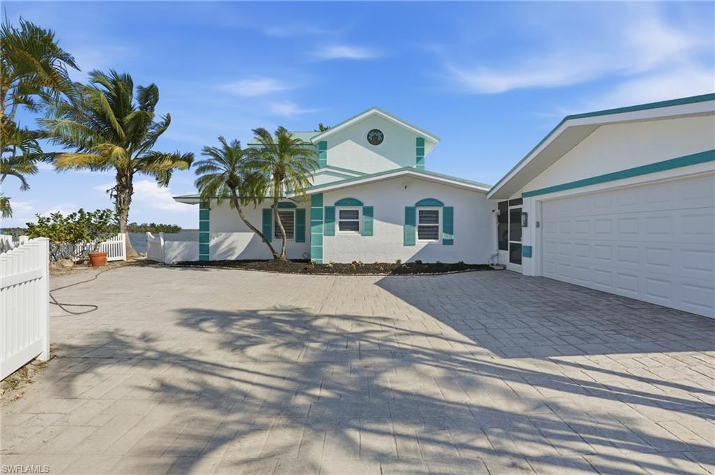View of front of property with stucco siding, decorative driveway, and a garage - Virtually Edited Image