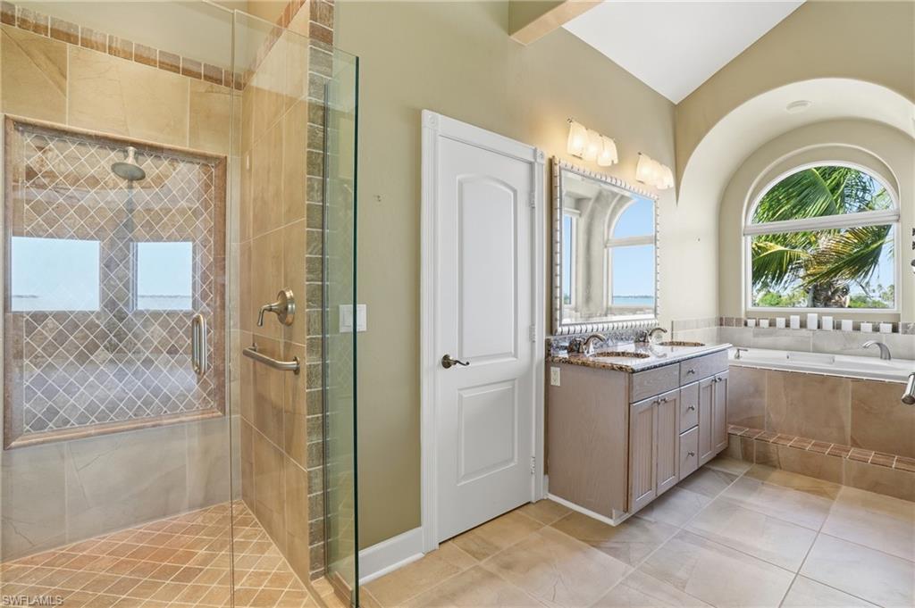 Full bath featuring vanity, a garden tub, light tile patterned floors, a stall shower, and vaulted ceiling - Virtually Edited Image