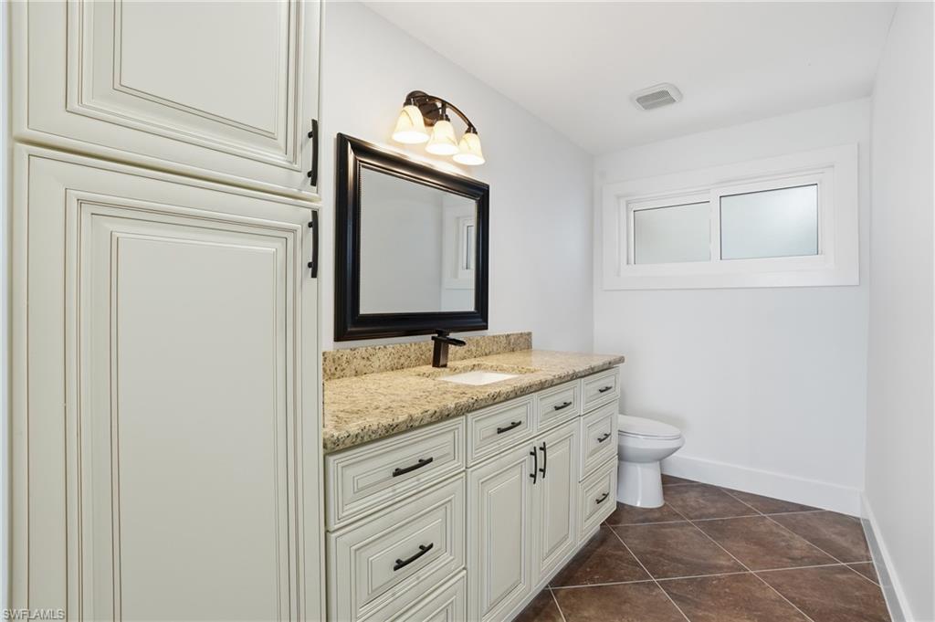 Bathroom with vanity and dark tile patterned flooring - Virtually Edited Image