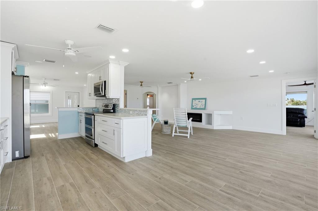 Kitchen with plenty of natural light, white cabinetry, open floor plan, appliances with stainless steel finishes, and recessed lighting - Virtually Edited Image