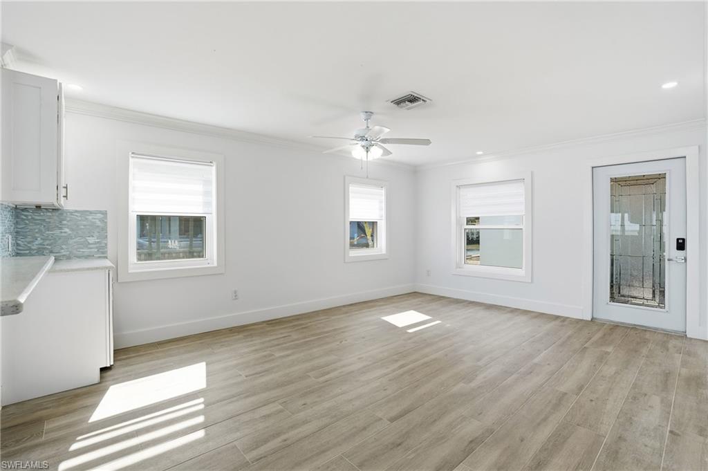 Unfurnished living room with crown molding, light wood-type flooring, a ceiling fan, and recessed lighting - Virtually Edited Image