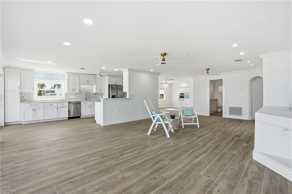 Kitchen with white cabinetry, open floor plan, recessed lighting, light countertops, and appliances with stainless steel finishes - Virtually Edited Image