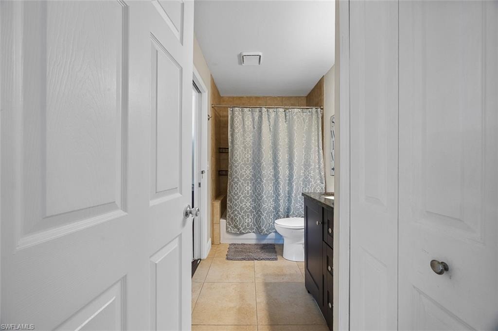 Bathroom featuring a dark wood vanity with a dark countertop, white toilet, and tiled flooring