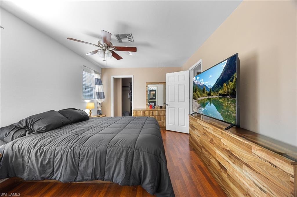 Bedroom featuring wood-finish flooring, a ceiling fan with integrated lighting, and a window with horizontal blinds