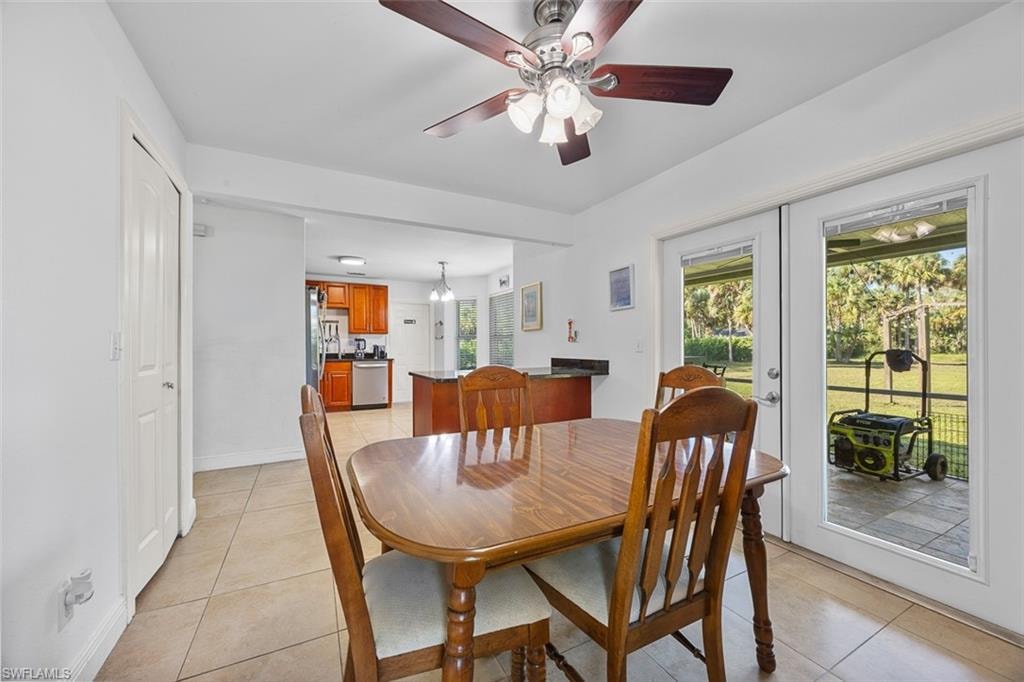 Bright dining area featuring tile flooring, a ceiling fan with integrated lighting, and white walls