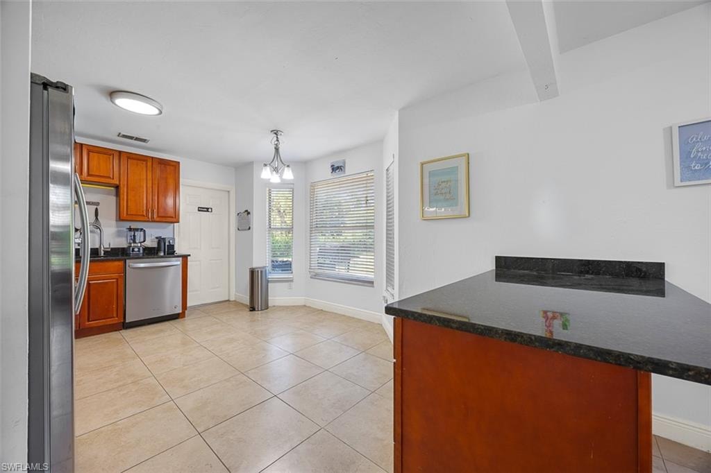 Kitchen featuring wood-finish cabinetry, stainless steel appliances, and a dark stone countertop