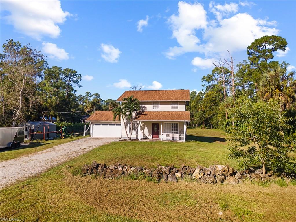 Two-story residence featuring an attached garage, a covered front porch, and a gravel driveway