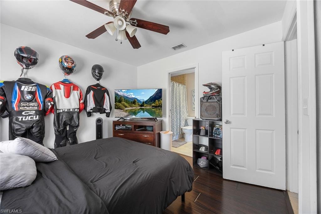 Spacious bedroom featuring dark wood-finish flooring, a ceiling fan with light fixture, and a built-in closet with a white paneled door