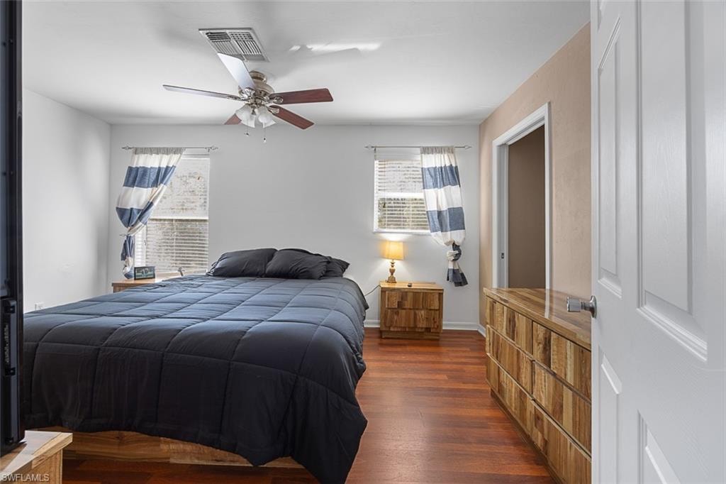 Bedroom featuring wood-finish flooring, a ceiling fan with integrated lighting, and a white paneled door