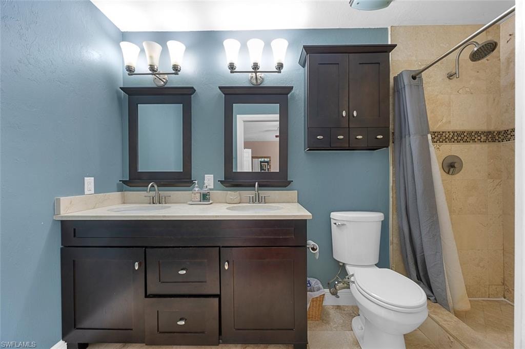 Double vanity featuring dark wood cabinetry, light-toned countertops, and dual framed mirrors