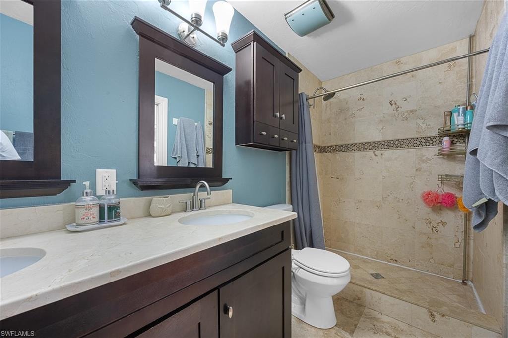 Double vanity with integrated sinks, stone-finish countertop, and dark wood cabinetry
