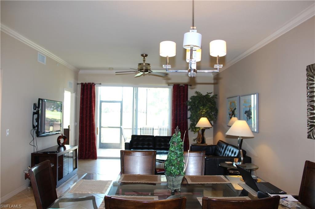 Tiled dining room with crown molding, a chandelier, and ceiling fan