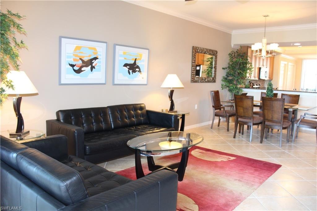 Living room featuring light tile patterned floors, crown molding, and a chandelier