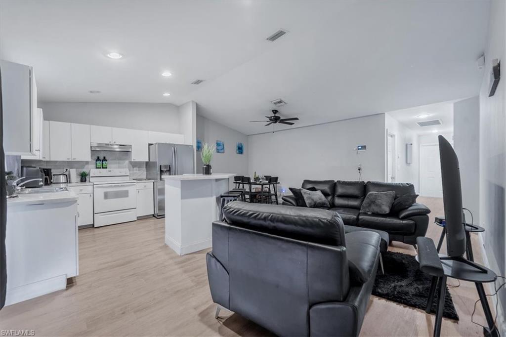 Spacious open-concept living area featuring wood-finish flooring, recessed lighting, and a ceiling fan