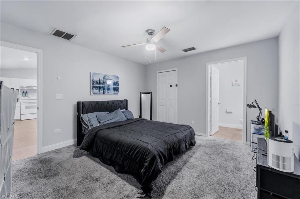 Spacious room featuring light gray walls, plush gray carpeting, a built-in ceiling fan, and two interior doorways