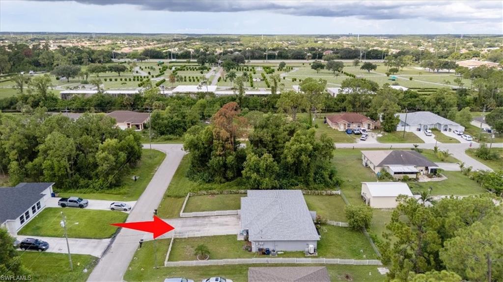 Aerial perspective showcasing a residential lot with a single-story home featuring a light gray roof and neutral exterior siding