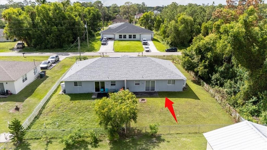 Expansive green lawn surrounds the property, featuring a light blue exterior, a gray shingle roof, and a privacy fence