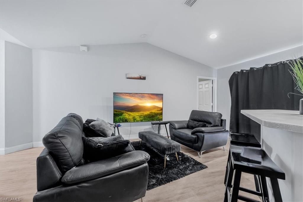 Living area featuring wood-finish flooring, vaulted ceilings, and recessed lighting