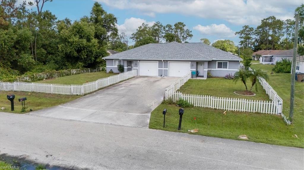 Duplex property featuring a light gray exterior with white trim, two single-car garages, and a shared paved driveway