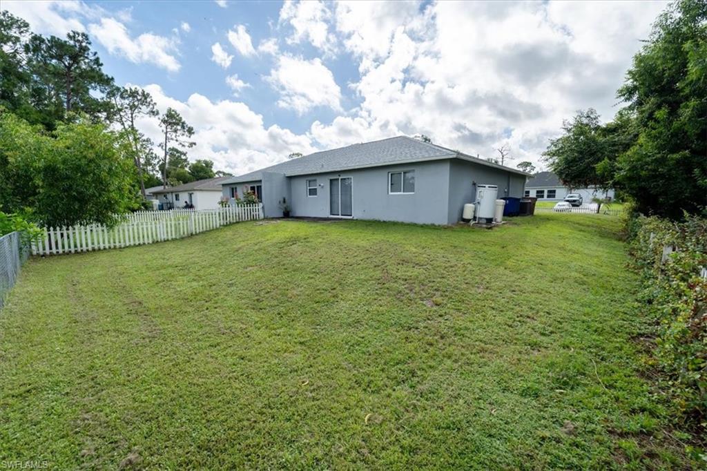 Expansive green lawn with a white picket fence partially enclosing the property