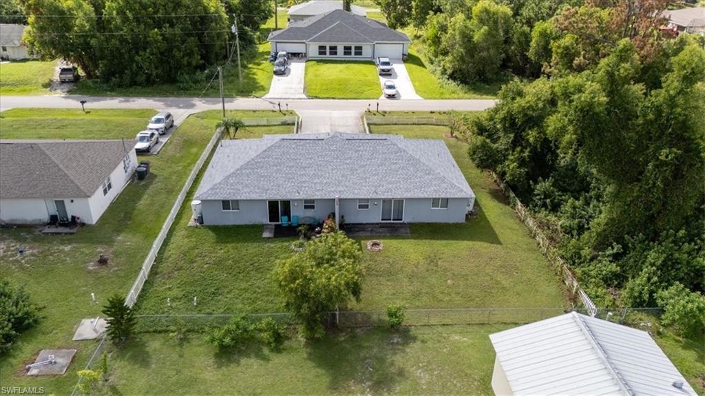 Expansive property featuring a grey shingle roof, light blue exterior siding, and a spacious green lawn