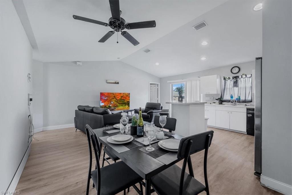 Open-concept living space featuring wood-finish flooring, vaulted ceilings, recessed lighting, and a modern ceiling fan