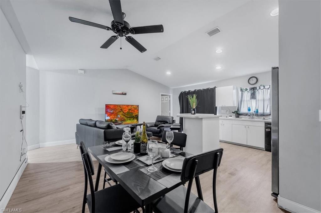 Open-concept living space featuring wood-finish flooring, a vaulted ceiling, and a black ceiling fan