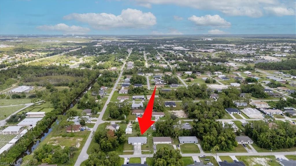 Aerial overview of a residential area featuring a single-story property with an attached garage and a paved driveway