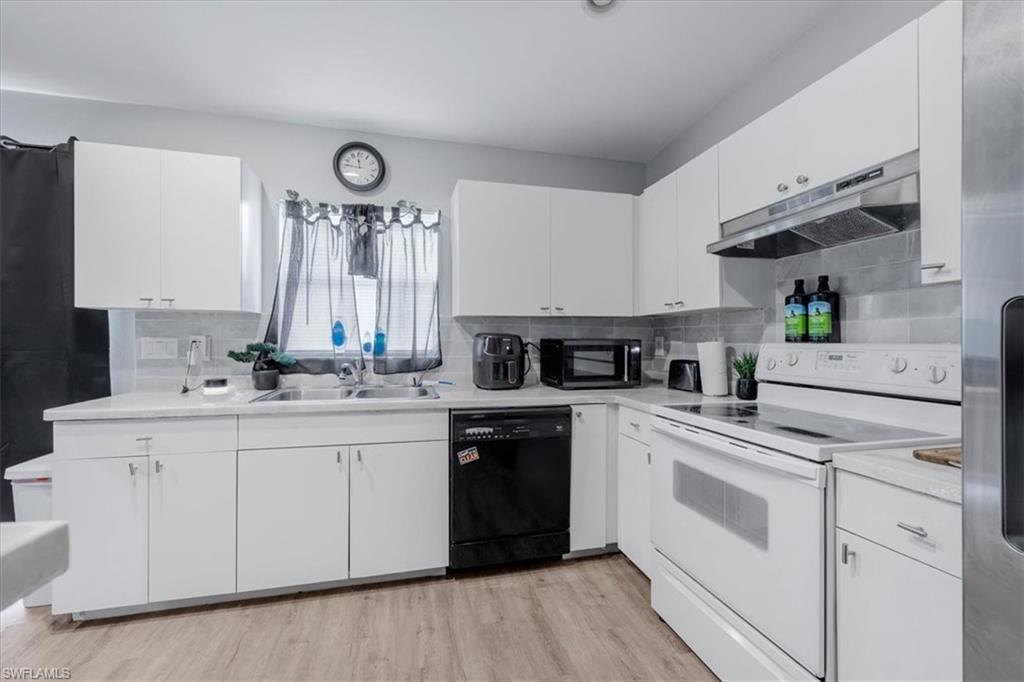 Kitchen featuring white cabinetry, light-toned countertops, tile backsplash, and wood-finish flooring