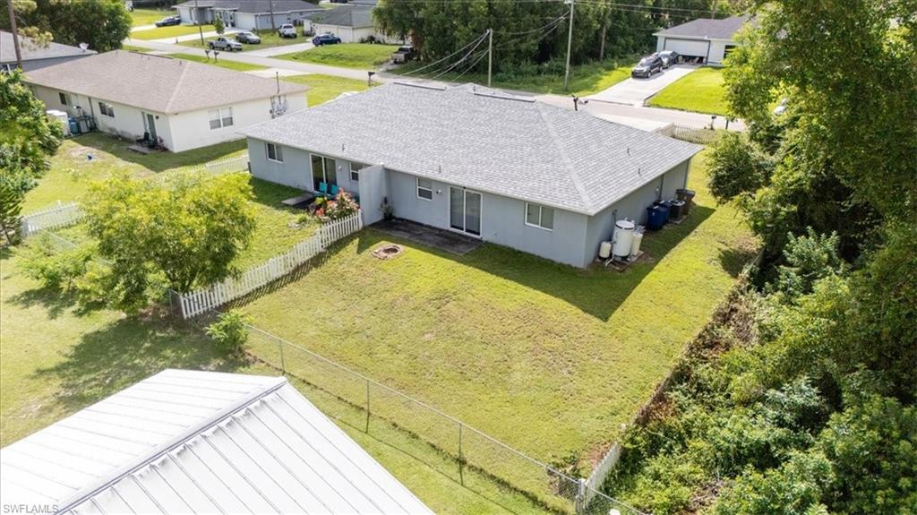 Expansive backyard featuring a manicured lawn, partial white picket fence, and chain-link fencing