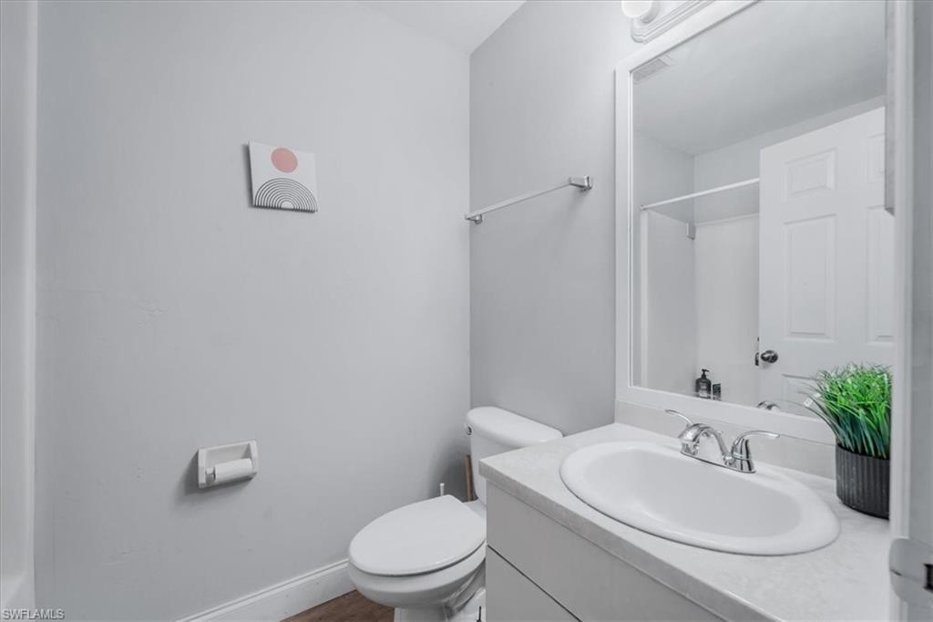 Bathroom featuring a white vanity with an integrated sink, chrome faucet, and expansive wall mirror