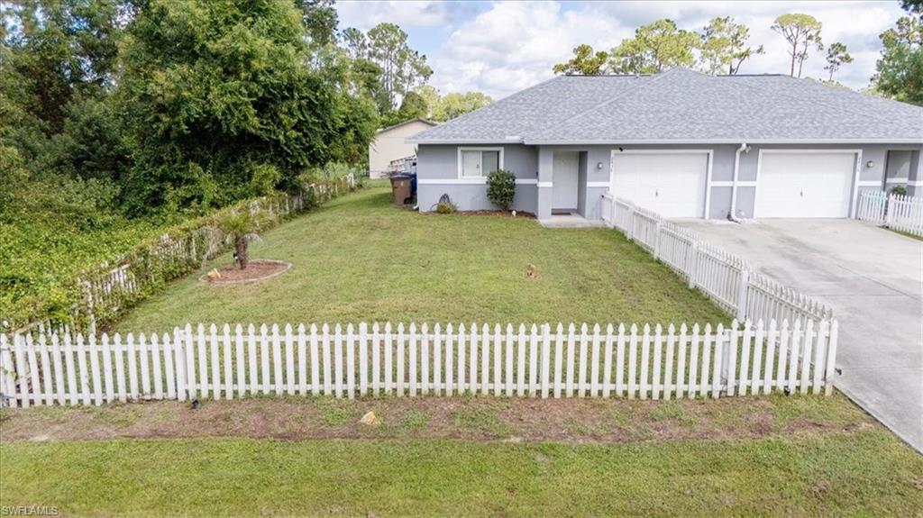 Gray exterior with a dark gray shingle roof and a white picket fence enclosing the front yard