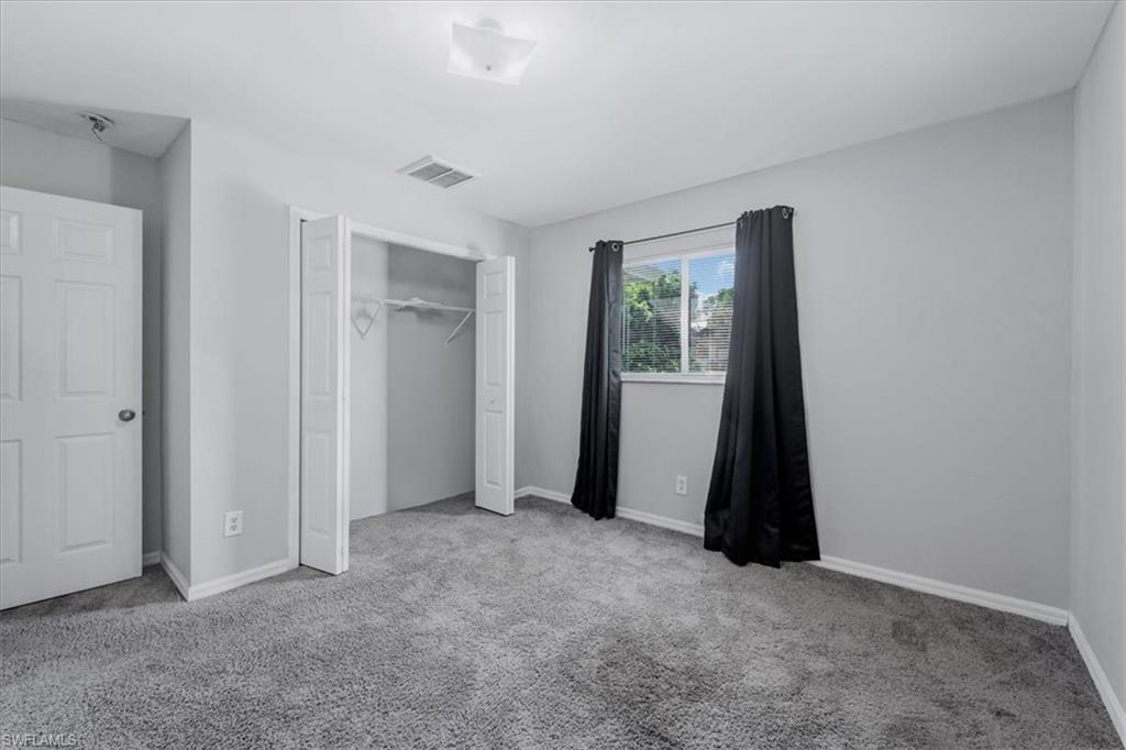 Carpeted room featuring a double-pane window, bi-fold closet doors, a white interior door, and a ceiling-mounted light fixture