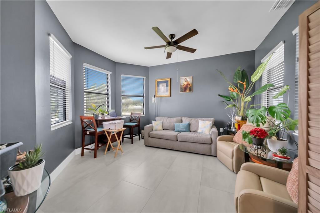 Spacious interior room featuring multiple windows with blinds, a ceiling fan, and light-toned tile flooring