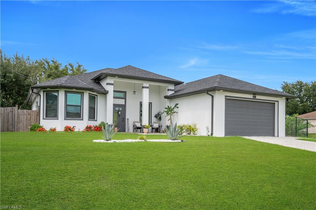 Contemporary stucco exterior with a dark shingle roof, a two-car garage, an inviting covered entry, and a manicured front lawn