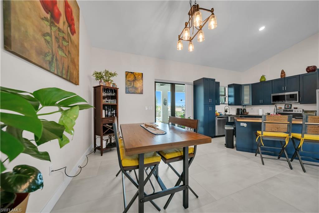 Open-concept kitchen and dining area featuring vaulted ceilings and light-toned tile flooring