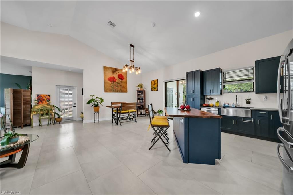 Spacious kitchen featuring dark cabinetry, a farmhouse sink, stainless steel appliances, and a central island with a wood-finish countertop