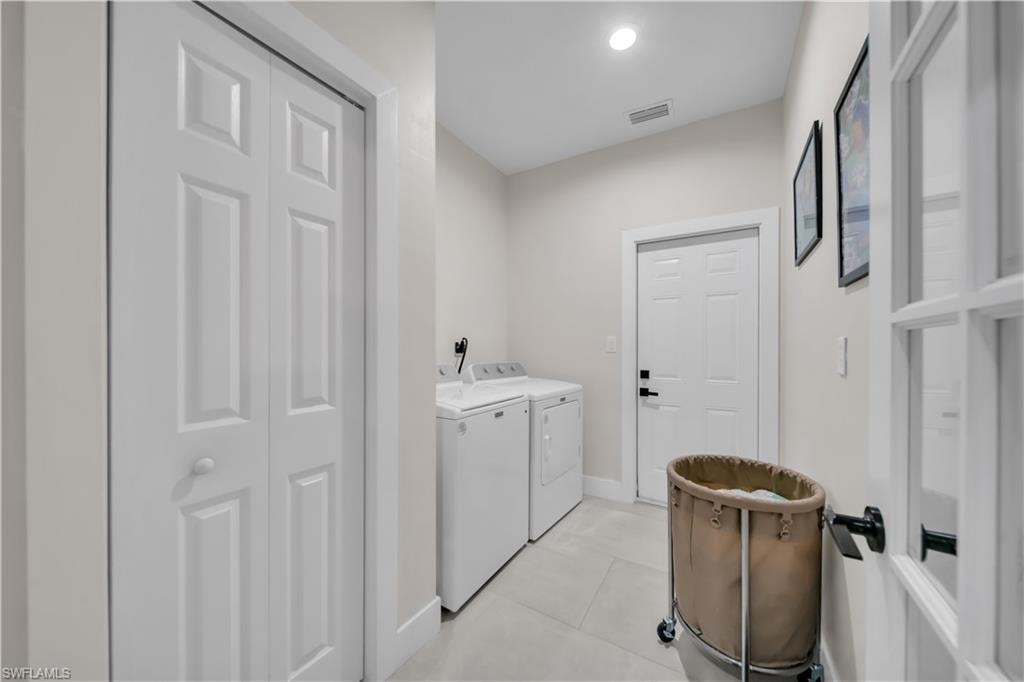 Utility space featuring bi-fold panel doors, a panel entry door with black hardware, and light-toned floor tiling