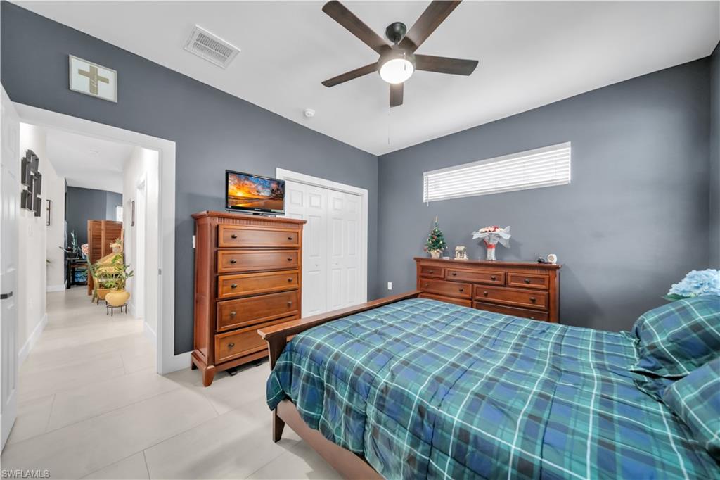 Bedroom featuring light-toned tile flooring, a ceiling fan with integrated lighting, and a horizontal window with blinds