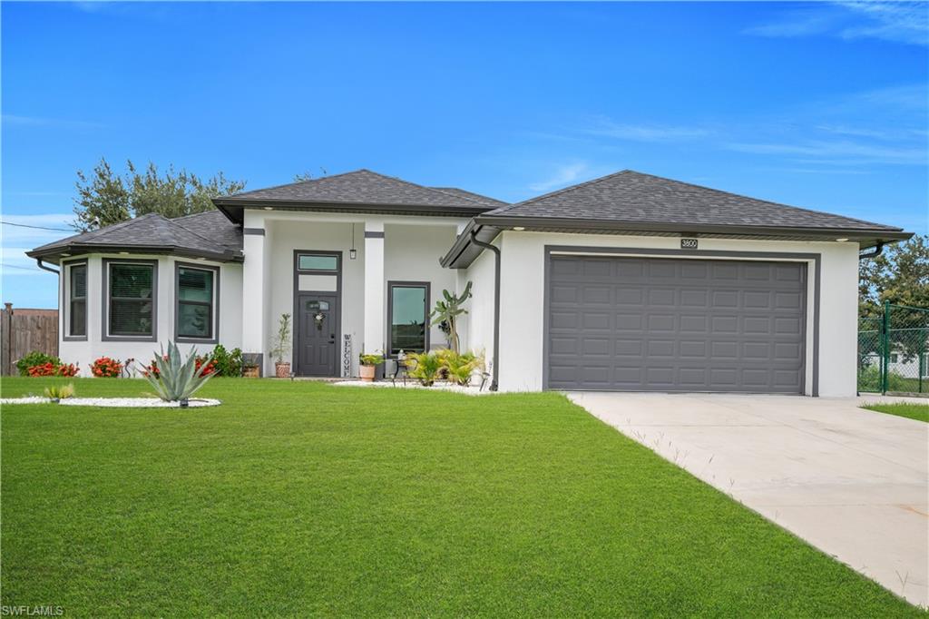 Contemporary white stucco exterior with dark trim accents, a two-car garage, a covered entry porch, and a bay window