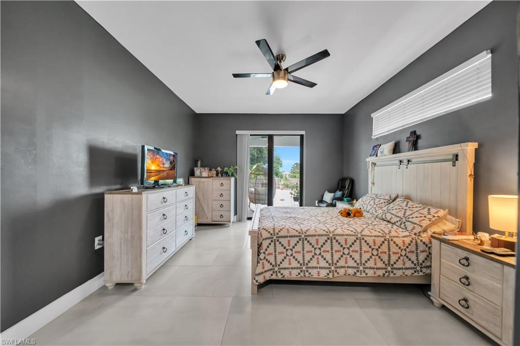Spacious room featuring neutral tile flooring, a dark accent wall, and a ceiling fan with integrated lighting