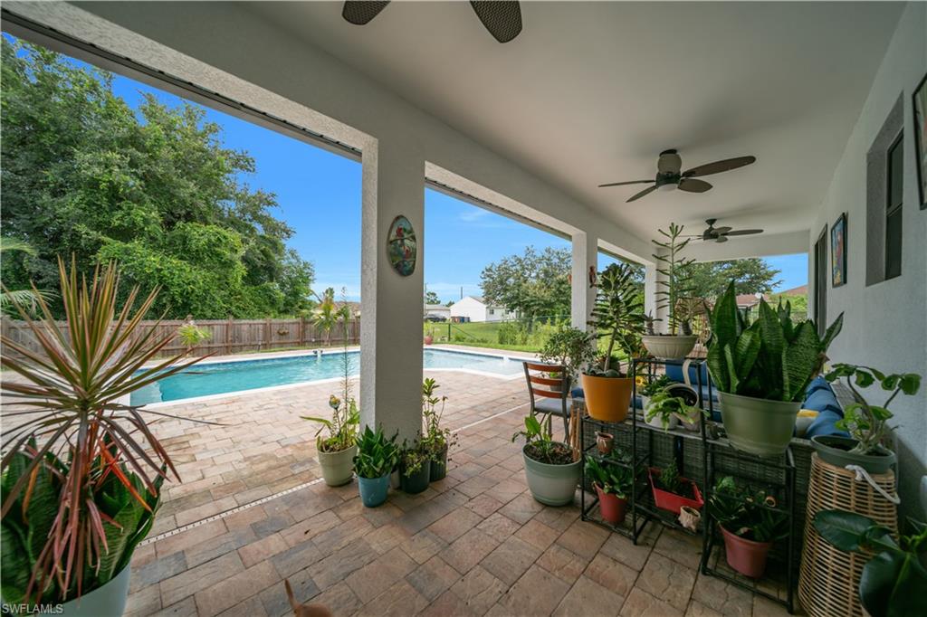 Expansive covered patio with paver flooring, multiple ceiling fans, and an adjacent swimming pool with a surrounding paver deck