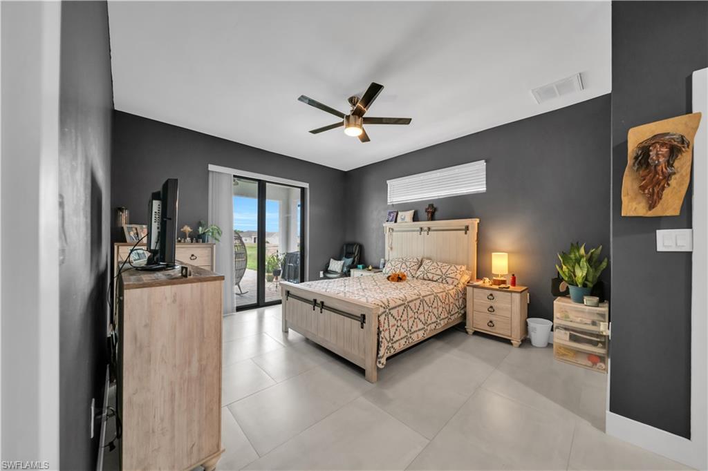 Spacious room featuring light-toned tile flooring, a dark gray accent wall, and a ceiling fan with integrated lighting