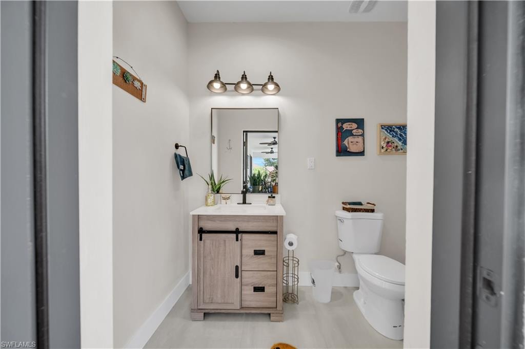 Bathroom featuring a light wood-finish vanity with a white countertop and rectangular sink, black faucet, and a rectangular mirror