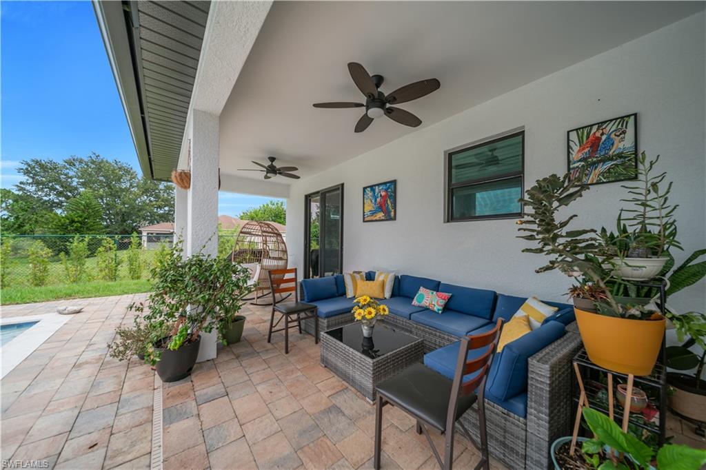 Expansive covered patio featuring paver flooring, multiple ceiling fans, and a solid exterior wall