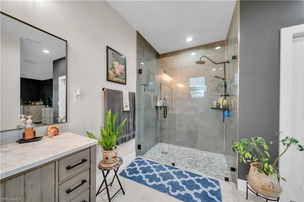 Spacious bathroom featuring a glass-enclosed shower with large format tile walls and a pebble floor
