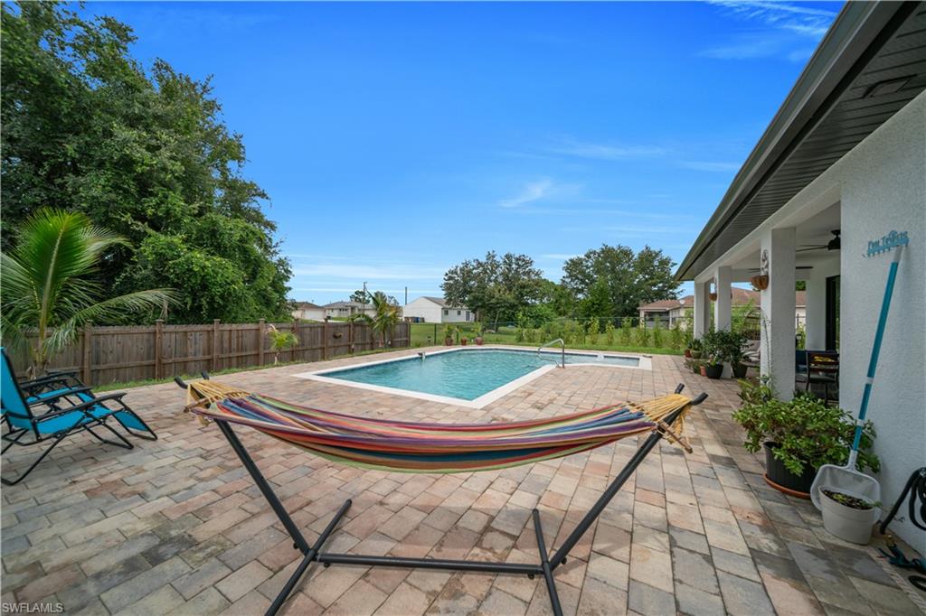 Outdoor living space featuring a paver patio, a rectangular swimming pool, an integrated spa, and a covered lanai