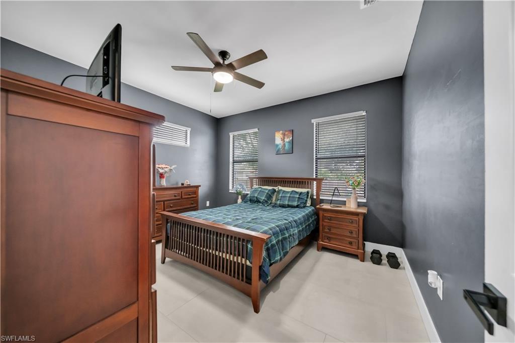 Spacious room featuring light-toned flooring, two windows with blinds, and dark-toned walls